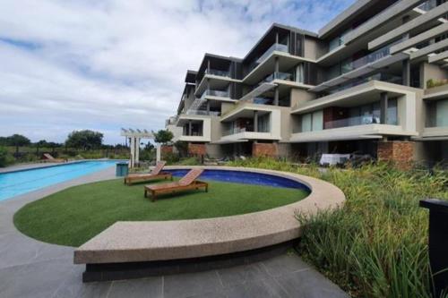 a large apartment building with a pool and two benches at Umhlangha Oceans Dunes in Umhlanga