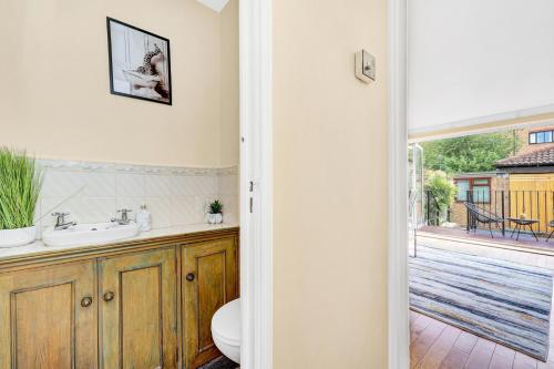 ein Badezimmer mit einem Waschbecken und einem WC sowie eine Terrasse in der Unterkunft Charming 3 Bedroom House near Canary Wharf in London