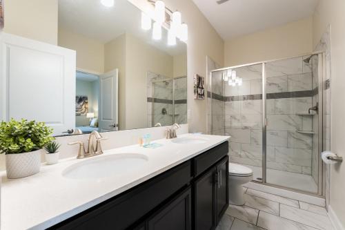 uma casa de banho com um lavatório, um chuveiro e um WC. em Spacious 8BR Villa by Disney World w Private Pool em Kissimmee