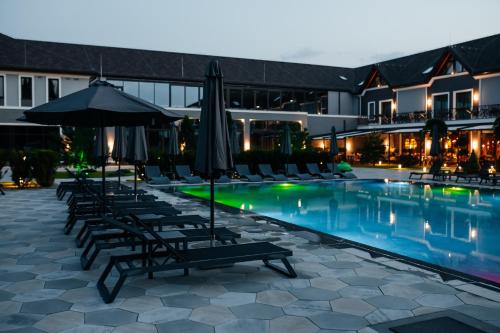 uma piscina do hotel com espreguiçadeiras e guarda-sóis em Underhill Resort&Spa em Bohorodchany