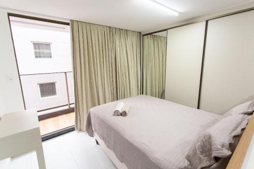 a bedroom with a bed and a large window at Unity Beira Mar de João Pessoa by Carpediem in Penha