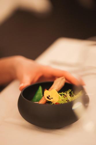 a person holding a bowl of food on a table at Chateau d'Urspelt in Urspelt