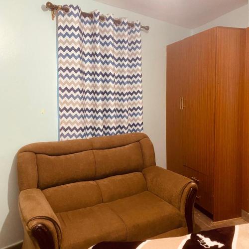 ein braunes Sofa im Wohnzimmer mit Fenster in der Unterkunft Studio Bnb Thika Town in Thika