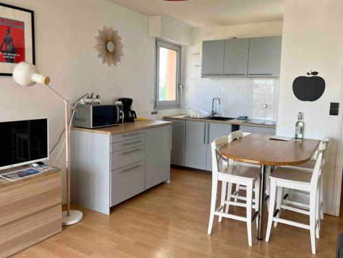 a kitchen with a table and chairs in a kitchen at Coralline, Appartement lumineux à 2 pas de la mer. in Wimereux
