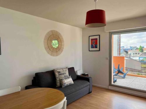 a living room with a couch and a table at Coralline, Appartement lumineux à 2 pas de la mer. in Wimereux