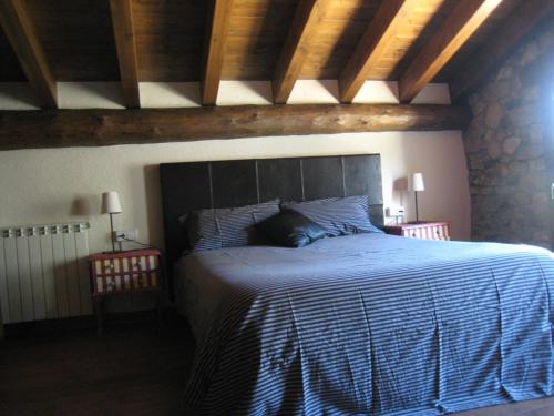 1 dormitorio con 1 cama con manta azul y blanca en Ca l'Escolà en Aransá