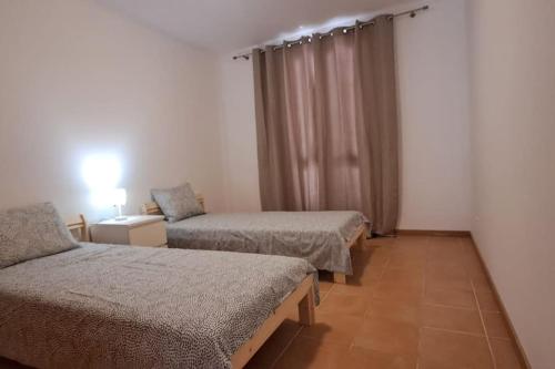 una stanza con due letti e una finestra di Casa das Lombas a Vila Baleira