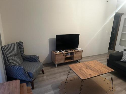 uma sala de estar com uma televisão e duas cadeiras e uma mesa em Kiralık Daire em Istambul