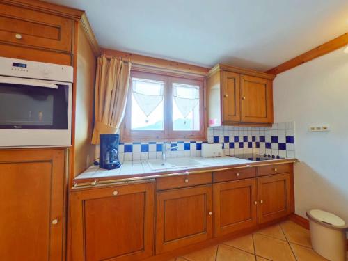 una cocina con armarios de madera y una ventana en Appartement Villard-sur-Doron, 4 pièces, 10 personnes - FR-1-594-198 en Villard-sur-Doron