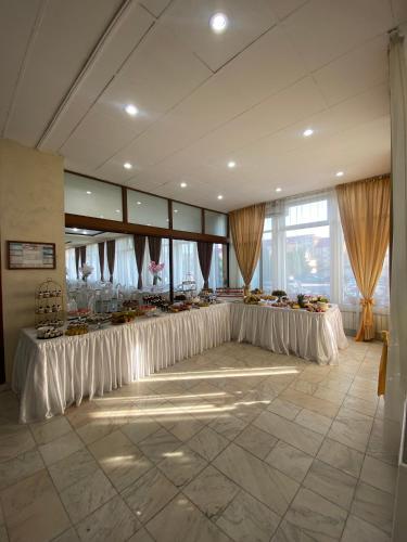 a banquet hall with white tables with flowers on them at Hotel Diana in Bistriţa