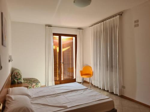 a bedroom with a bed and a chair and a window at Hotel Florida in Limone sul Garda