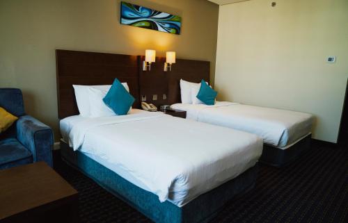 a hotel room with two beds and a couch at Best Western Premier Muscat in Muscat