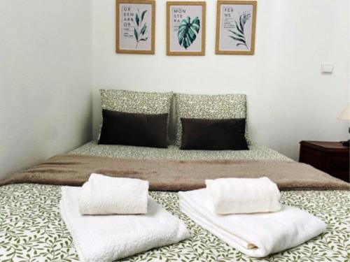um quarto com uma cama com duas almofadas em SwordFish Casa da Luz em Peniche