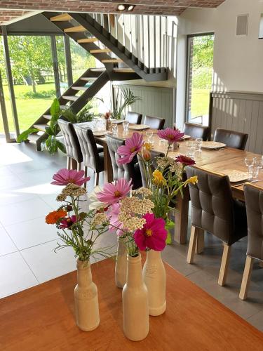 a dining room with a table with flowers in vases at Hotel - B&B PassaDia in Zwevegem