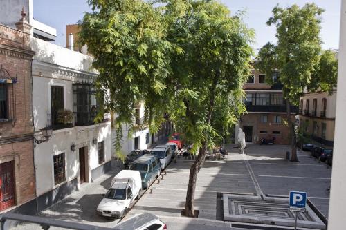 a street with cars parked next to a tree at Plaza de los Curtidores sevilla in Seville