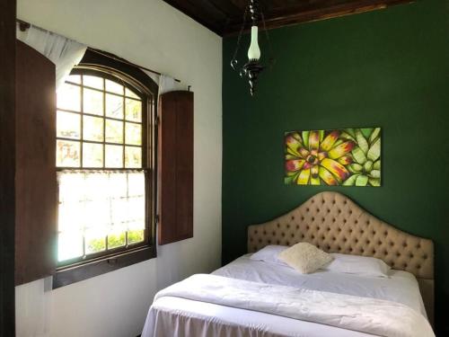 1 dormitorio con cama y pared verde en Casa Temporada com Tranquilidade e Aconchego - Petrópolis - RJ, en Petrópolis