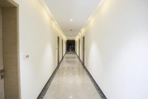 pusty korytarz w budynku z białymi ścianami i sufitami w obiekcie Hotel Grand Vasaante w mieście Bhīlwāra