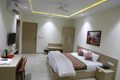 Pokój hotelowy z łóżkiem, stołem i biurkiem w obiekcie Hotel Grand Vasaante w mieście Bhīlwāra