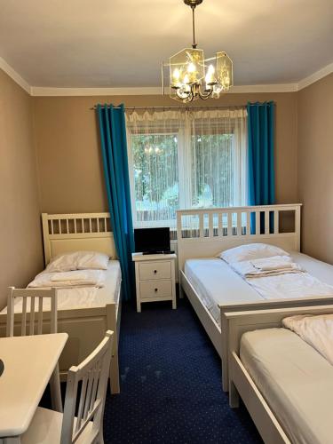 a bedroom with two beds and a table and a laptop at Noclegi AirportPark in Pyrzowice