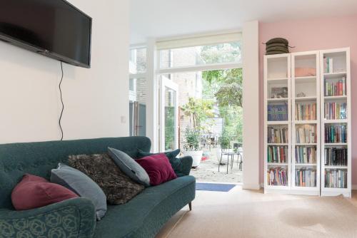 una sala de estar con un sofá verde con almohadas en B&B Amsterdam West en Ámsterdam