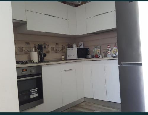eine Küche mit weißen Schränken und einer Mikrowelle in der Unterkunft LME Residence in Târgovişte