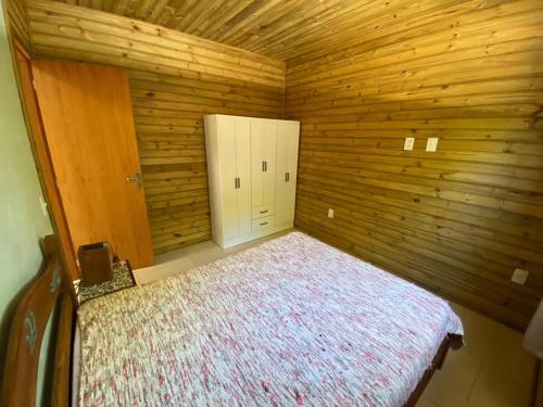 1 dormitorio con 1 cama en una habitación de madera en Casa do Bosque, 500m da praia Campeche, en Florianópolis