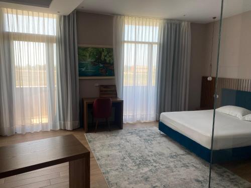 1 dormitorio con 1 cama, escritorio y ventanas en Bolv Hotel, en Durrës