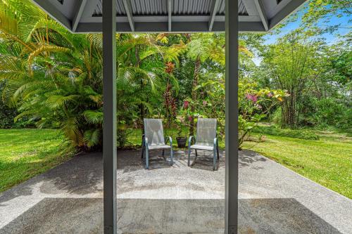 two chairs sitting on a patio in a garden at Hale Olena Ohana | 31+ day rental in Keaau