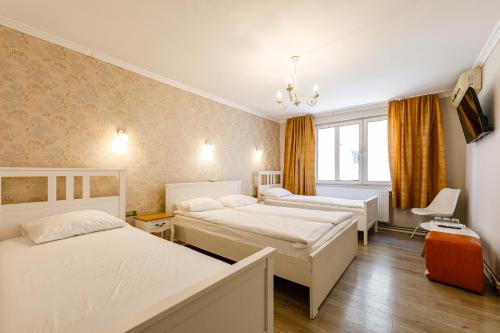 a hotel room with three beds and a window at Pensiunea Bella in Arad