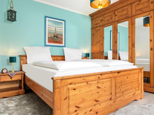 una camera da letto con un grande letto in legno con lenzuola bianche di Ostsee Residenz Meeresblick Albatros a Insel Poel