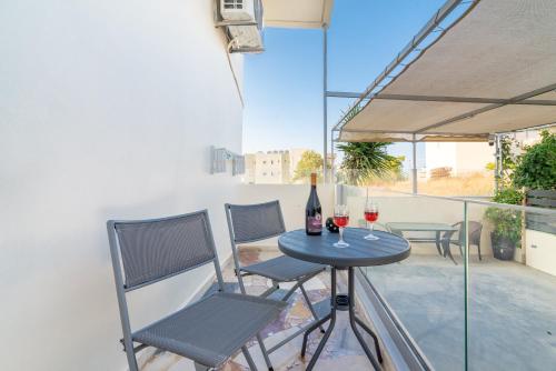 a table and chairs on a balcony with wine glasses at Studio for Couples near Beach in Gázion