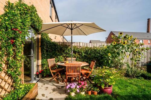 a table and chairs with an umbrella in a garden at Artist's Garden on Wolsey Island in Leicester