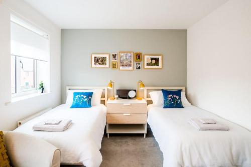 two beds in a room with a desk and a window at Artist's Garden on Wolsey Island in Leicester