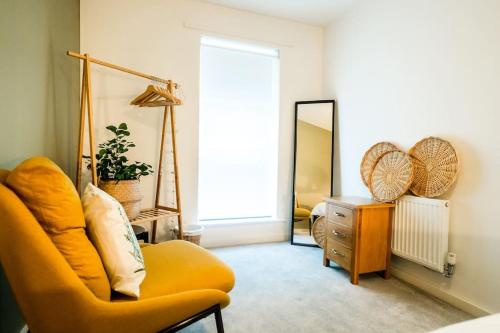 a living room with a yellow chair and a mirror at Artist's Garden on Wolsey Island in Leicester