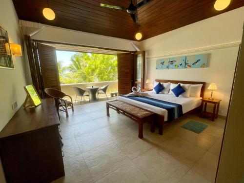 a bedroom with a bed and a large window at Khomba Lodge in Tangalle