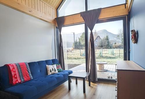 salon z niebieską kanapą i dużym oknem w obiekcie Ostoja Radków całoroczny domek z balią w mieście Radków