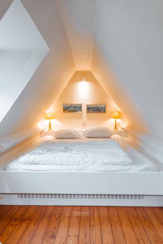 a bedroom with a white bed in the attic at La Marjolaine in De Haan