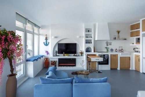 a living room with a blue couch and a kitchen at Anna Maria Santorini - Greek Suite & Large sea terrace Arcadia in Odesa