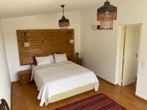 a bedroom with a bed with a wooden headboard and chandeliers at Cama da Vaca in Mato Porcas