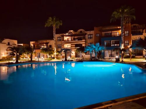 a large blue swimming pool at night with buildings at Vila ZINA Port Ghalib in Port Ghalib