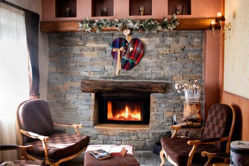 a living room with a brick fireplace with two chairs at Maison Cly in Chamois