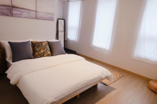 a bedroom with a white bed and two windows at Blue Casa in Seogwipo