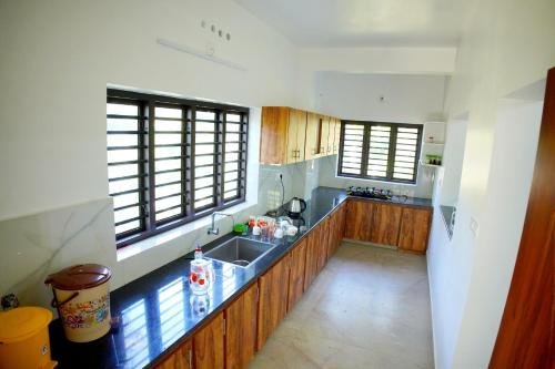 een grote keuken met houten kasten en een wastafel bij Vaishnavam Double Bedroom Villa in Thekkady