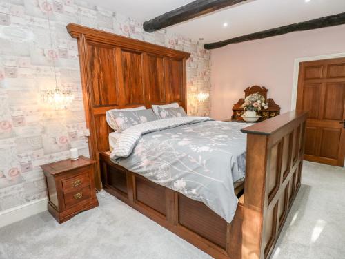 a bedroom with a wooden bed with a wooden headboard at Shore Hall in Littleborough