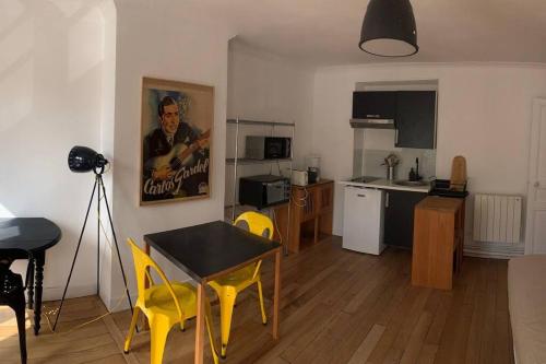 a kitchen with a table and yellow chairs in a room at St ouen centre 20mn de châtelet Ligne 14 in Saint-Ouen