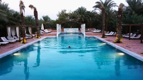 a person swimming in a large pool with palm trees at Al Moudira Hotel in Luxor