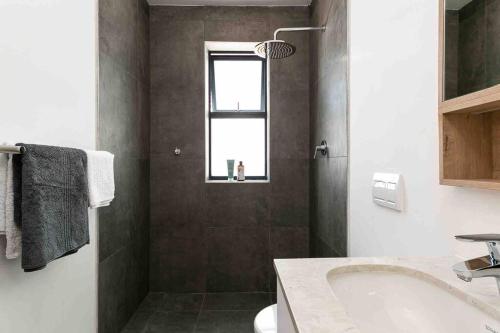 een badkamer met een bad, een wastafel en een raam bij The Palm Flats - Palm Paradise in Kaapstad