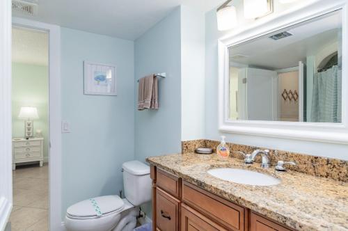 a bathroom with a sink and a toilet and a mirror at Renovated Condo Offering Free Beach Access!! in Marco Island
