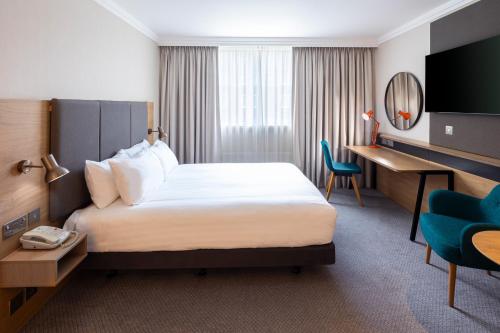 ハイ・ウィカムにあるHoliday Inn High Wycombe M40, Jct.4, an IHG Hotelのベッドとデスクが備わるホテルルームです。