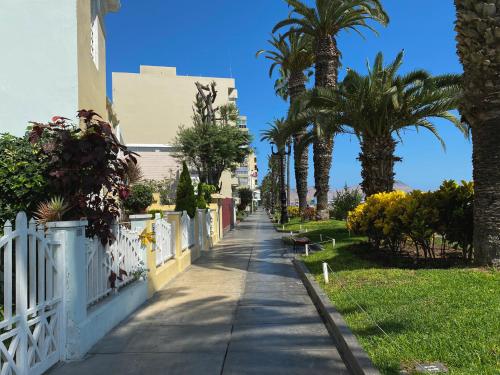 a sidewalk with palm trees and a white fence at Villa La Punta in Lima